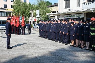Postroj gasilcev. Na levi je namestnik poveljnika Gasilske zveze Sevnica Matjaž Kovač, v ozadju so praporščaki, na desni strani pa postrojeni gasilci.