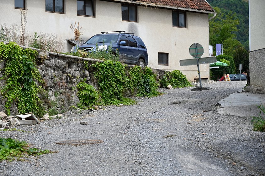 Fotografija kamnitega zidu ob cesti v središču kraja