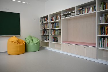 Na fotografiji je knjižnica z bralnim kotičkom in blazinami za sedenje 