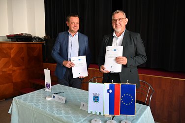 Župan Srečko Ocvirk in direktor Komunale d. o. o. Sevnica Mitja Udovč v rokah držita mapi, v katerih so podpisane pogodbe za izvedbo projekta 